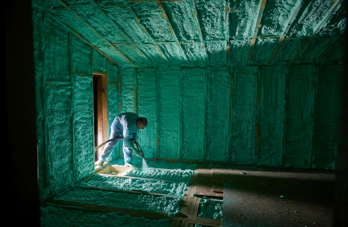 pracownik natryskujący piankę poliuretanową do izolacji domu o drewnianej ramie
